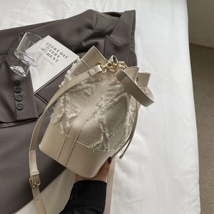 Close-up of beige denim bucket bag featuring frayed quilted edges and leather trim details