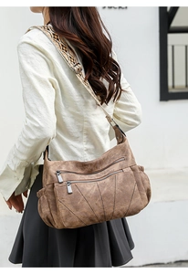 Detailed view of brown PU leather crossbody bag with ethnic style woven wide shoulder strap