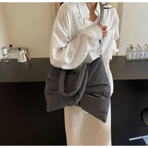 Detail of grey oversized bow tote bag with padded texture and silver metal hardware