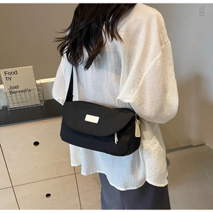 Minimalistische schwarze Nylon-Umhängetasche, präsentiert an einem Model mit weißem Hemd