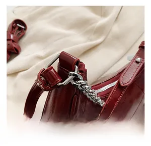 Détail du sac rouge en similicuir crocodile avec chaîne en argent et crochet métallique