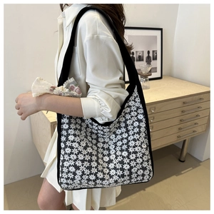 Detail view of black and white lace floral tote bag with a wide black shoulder strap