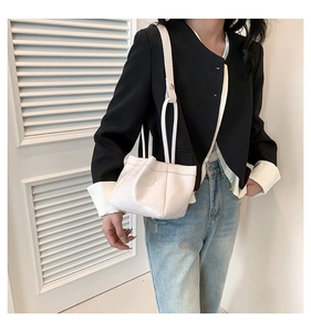 Detail of white crocodile embossed PU leather handbag with elegant pleats and shoulder strap