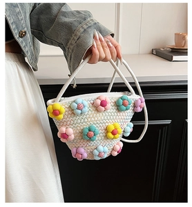 Detail of white woven handbag featuring colorful fabric floral decorations and rope handles