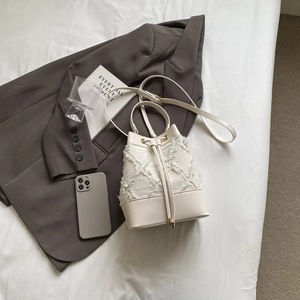 Top-down view of cream bucket bag with tweed texture, drawstring closure and leather straps