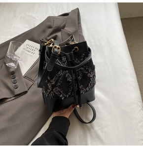 Detail of denim quilted bucket bag with frayed edges and drawstring closure