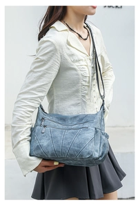 Detail view of light blue PU leather crossbody bag with vintage washed texture and stitching