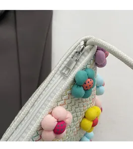Close-up of smooth silver zipper and colorful 3D fabric flowers on white woven bag