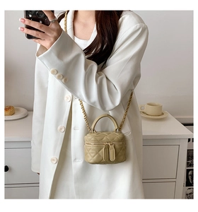 Detail of khaki quilted PU leather mini box bag with gold chain strap on lifestyle setting