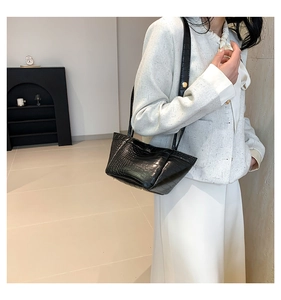 Detail of black faux crocodile texture shoulder bag on cream tweed outfit