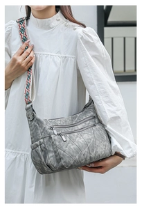 Detail of grey PU leather crossbody bag with vintage texture and bohemian woven strap