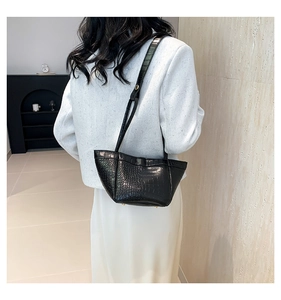 Detailed view of black crocodile pattern PU leather shoulder bag on model in minimalist setting
