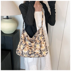 Close-up of a high-capacity black shoulder bag featuring vibrant yellow daisy floral prints