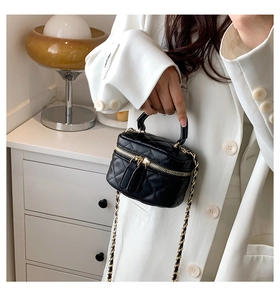 Detail of black quilted mini bag featuring golden dual zippers and chain strap in daily life