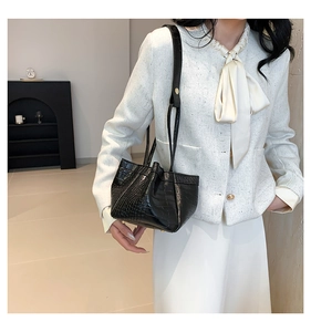Detail of elegant black crocodile pattern PU leather handbag with drawstring design
