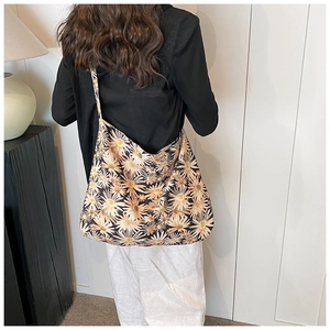 Detail showing the floral daisy pattern on a large canvas tote bag worn by a model