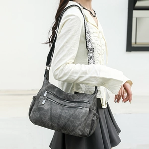 Close-up of multi-pocket dark grey PU leather crossbody bag with ethnic woven strap