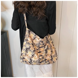 Rear view of a large tote bag featuring daisy floral patterns worn on the shoulder