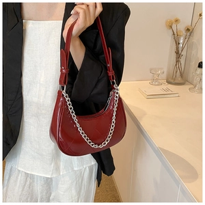 Gros plan sur le sac en demi-lune rouge foncé avec matelassage et chaîne argentée