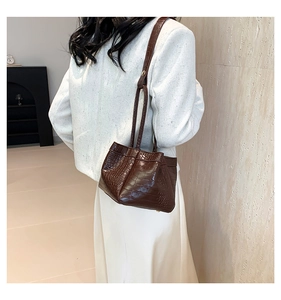Close-up of a dark brown crocodile pattern PU leather shoulder bag worn by a model
