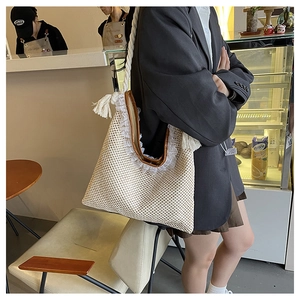 Detailed view of beige woven tote bag with white lace trim and thick rope straps