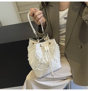 Close-up of stylish white denim quilted bucket bag featuring elegant gold metal hooks