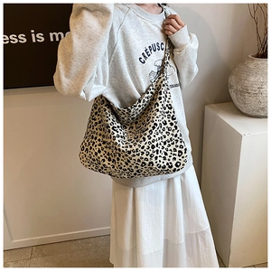 Detailed shot of leopard print canvas tote bag carried by a model in casual wear