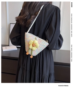 Detail of woven crossbody bag featuring a bright sunflower motif and elegant pearl clasp