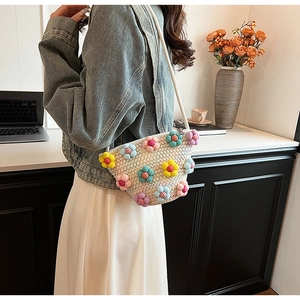 Detail view of woven crossbody bag featuring colorful 3D floral accents and white rope strap