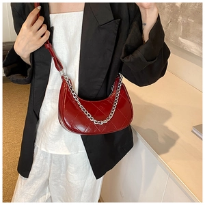 Détail du sac croissant en cuir PU rouge matelassé avec une chaîne argentée