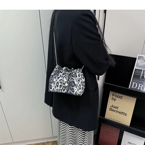 Detail of trendy leopard print bucket bag with silver chain and pearl drawstring charms