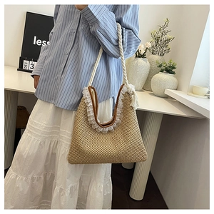Detailed view of woven straw tote bag with delicate white lace trim and cotton rope handles
