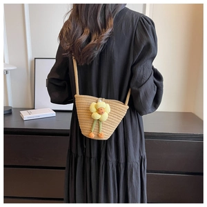 Detailed back view of a straw bucket bag with a yellow plush flower on a black dress