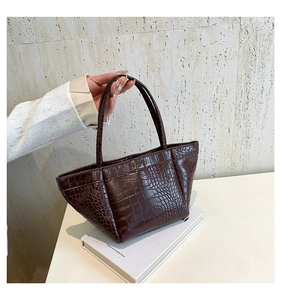Close-up of a vintage dark brown tote bag with crocodile pattern and slim handles