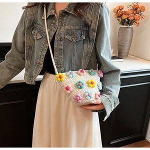 Detail of white straw bucket bag with colorful 3D floral pom-poms and thin cord strap