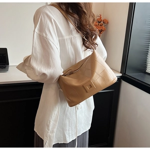 Detail of camel hobo bag showing irregular stitched panels and square metal buckle