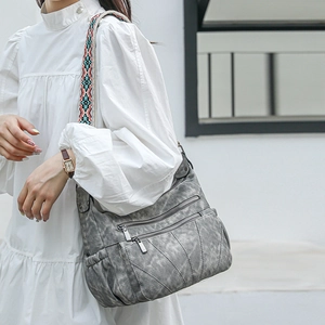 Close-up of a dark grey PU crossbody bag with ethnic style woven strap and metal zippers