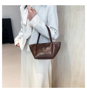 Close-up of dark brown crocodile pattern PU leather handbag with elegant textured detail