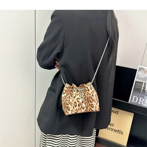 Detailed view of leopard print mini bucket bag with chain strap and pearl charms on model