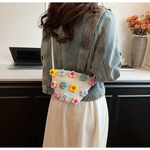 Detail of a mini woven crossbody bag with colorful 3D fabric flowers and cream texture