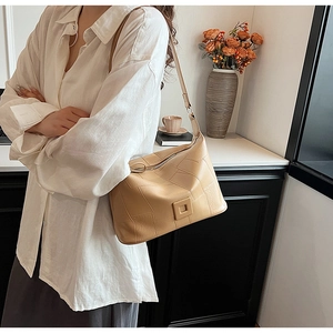 Close-up of beige PU leather shoulder bag with quilted stitching worn by model