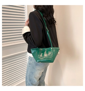 Detail of green crocodile pattern PU leather shoulder bag worn by model in casual style