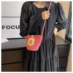 Detail of red and white woven crossbody bag with sunflower decor and pearl accent