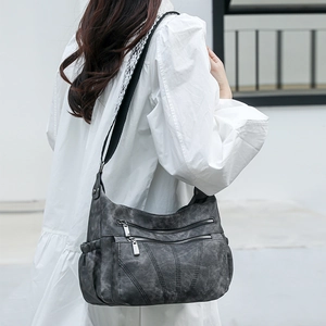 Detail view of charcoal gray PU leather crossbody bag with dual zippers and woven strap