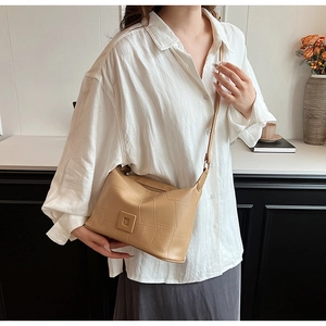 Close-up of khaki PU leather crossbody bag with geometric texture on a white shirt model