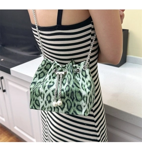 Detail of green leopard print bucket bag featuring pearl charms and silver chain strap