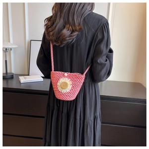 Detail of red and white woven crossbody bag with daisy charm and pearl lock on model