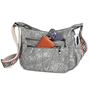 Detail of grey crossbody bag showing functional multi-zipper pockets and woven strap