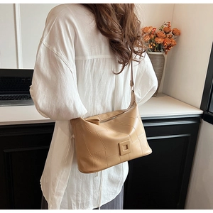 Detail showing geometric stitching and square buckle on light brown PU leather crossbody bag