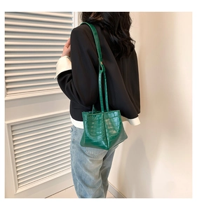 Detail shot of bright green crocodile embossed bucket bag with long thin shoulder straps